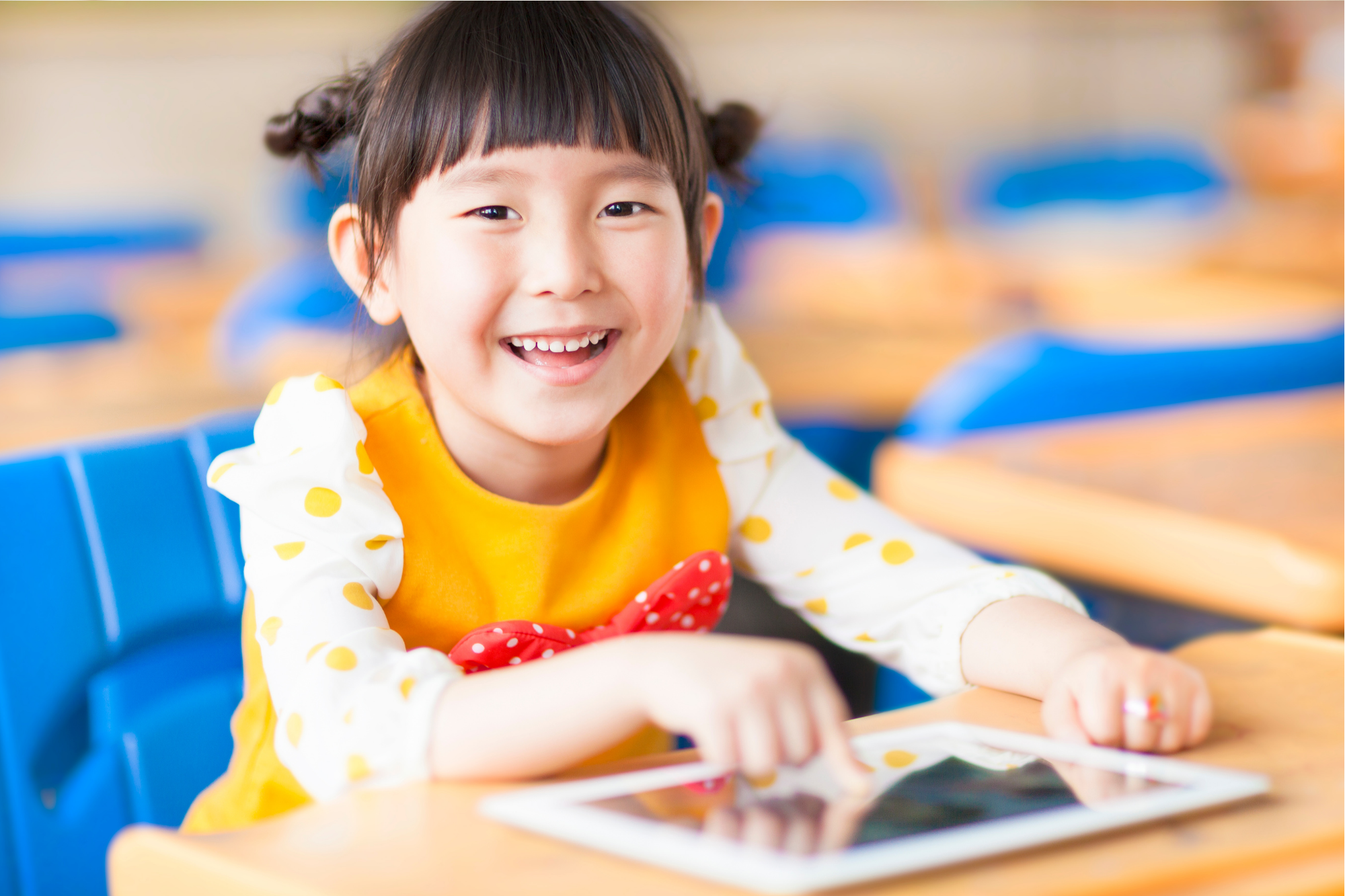 Young girl smiling at the camera with an iPad in her hands